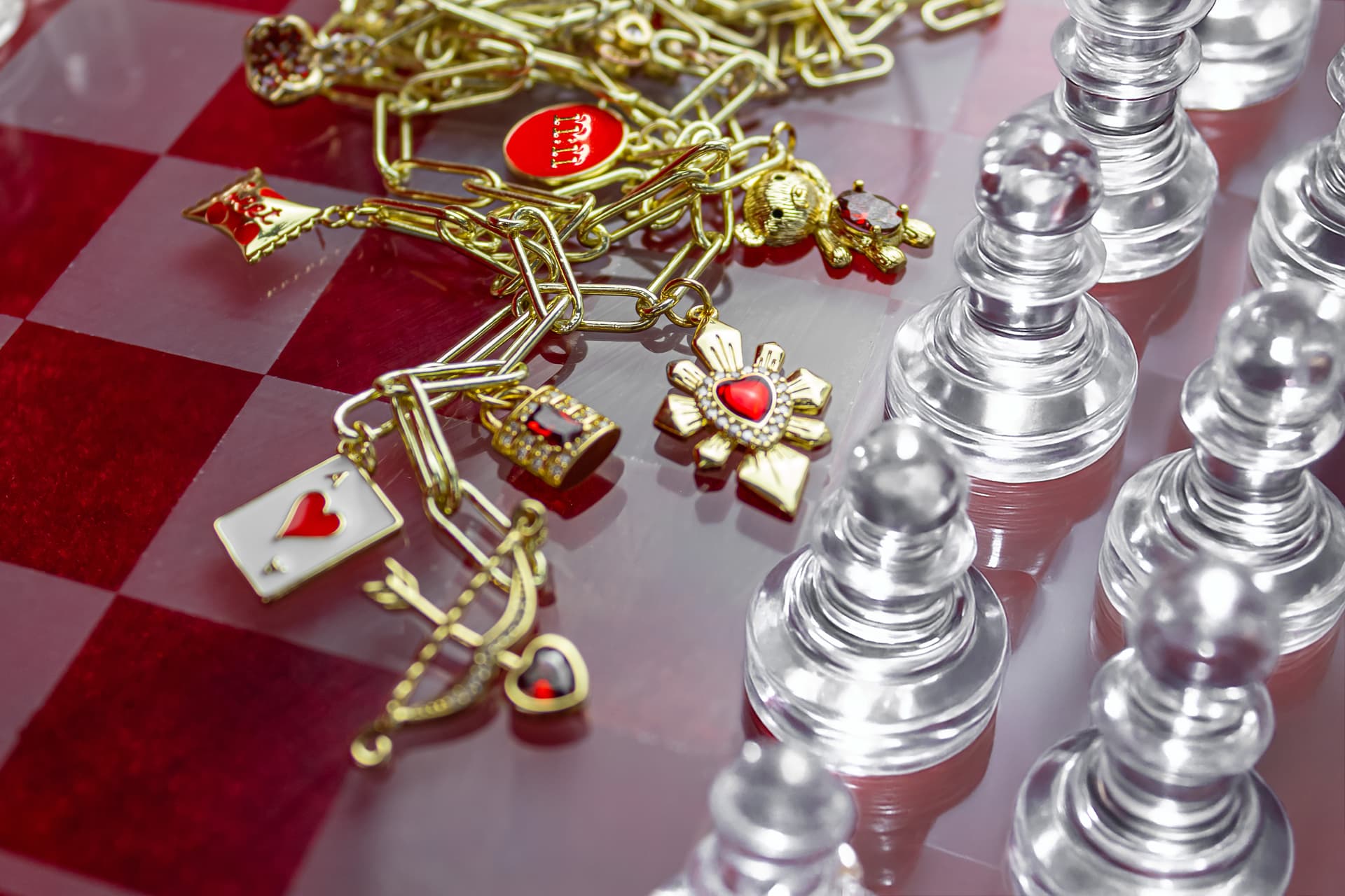 Chessboard with a gold bracelet on it with many gold charms with red stones